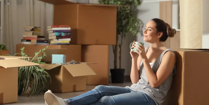 Woman sitting among moving boxes in a home, getting a house ready to sell