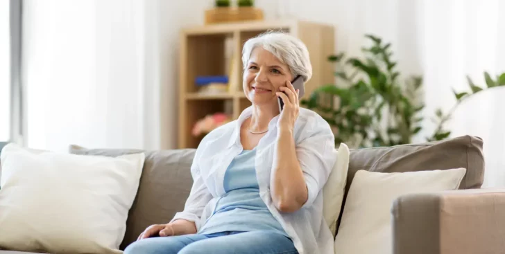 Woman sitting on a couch talking on the phone about selling her home