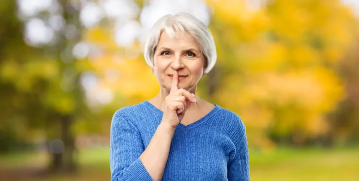 Woman holding a finger to her lips, representing what not to tell your Realtor when selling