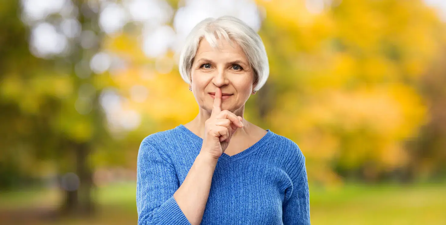 Woman holding a finger to her lips, representing what not to tell your Realtor when selling