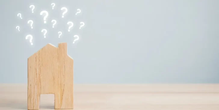 Wooden house with question marks above it, representing why you need a Realtor to sell your house