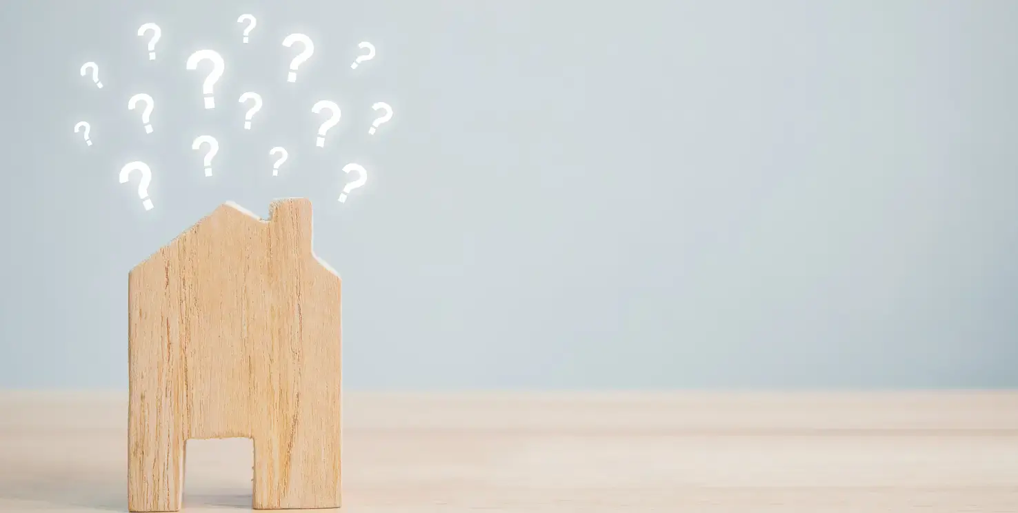 Wooden house with question marks above it, representing why you need a Realtor to sell your house