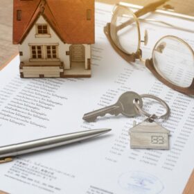 Pen and glasses resting on signed closing documents for the sale of a trust-held home.