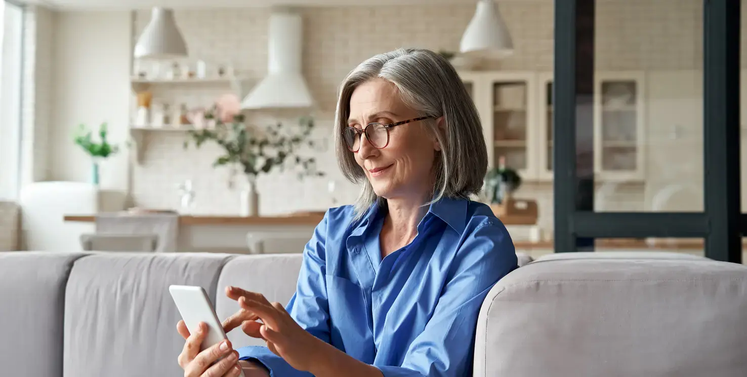 Woman sitting on a couch using her phone to contact a Realtor