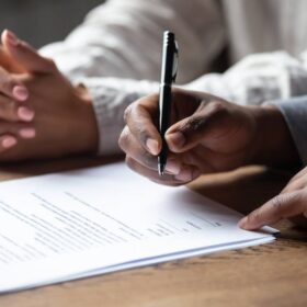 Older couple signing closing documents for selling a house in a trust before death