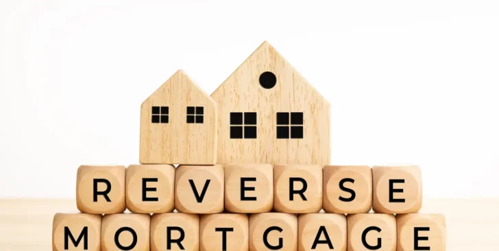Wooden blocks spelling reverse mortgage with two house models on top