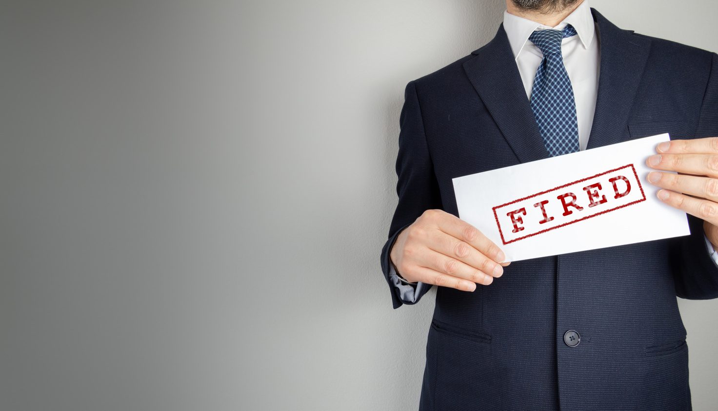 Male Realtor holding a sign that says 'Fired'