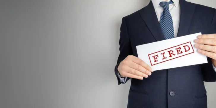 Man in a suit holding a sign that says fired, representing how to fire a Realtor